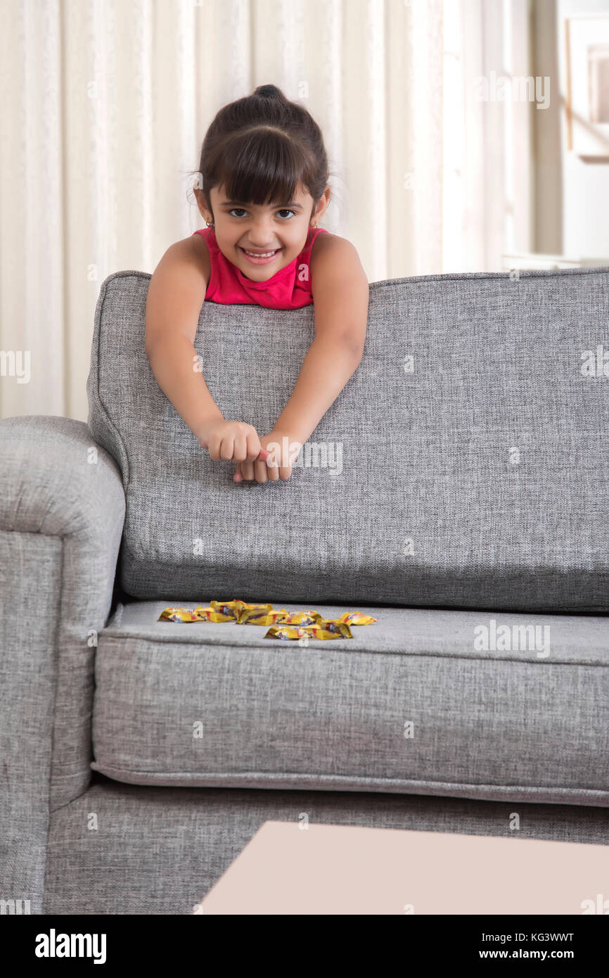Petite fille s'appuyant sur canapé avec des bonbons au chocolat Banque D'Images