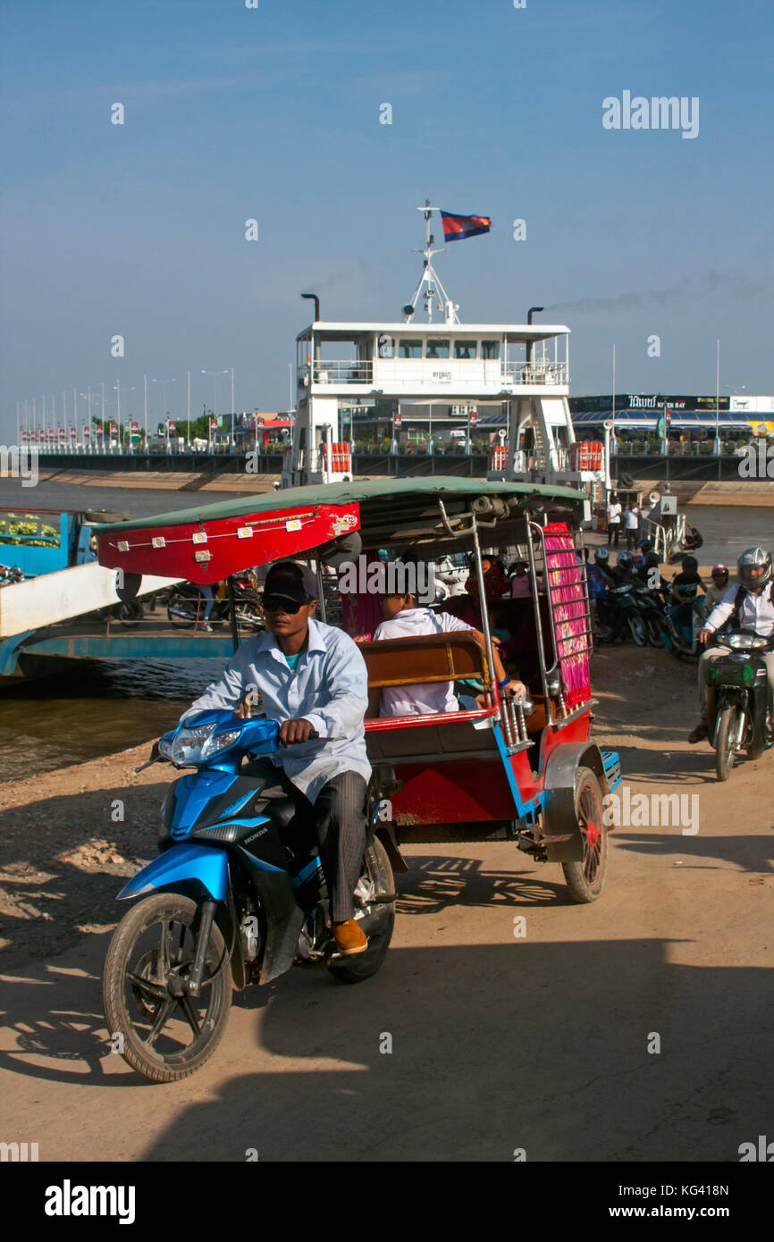 Un homme est au volant d'un tuk tuk qui transporte des passagers qui ont été transportés de l'autre côté de la rivière du Mékong sur un ferry à Phnom Penh, Cambodge. Banque D'Images