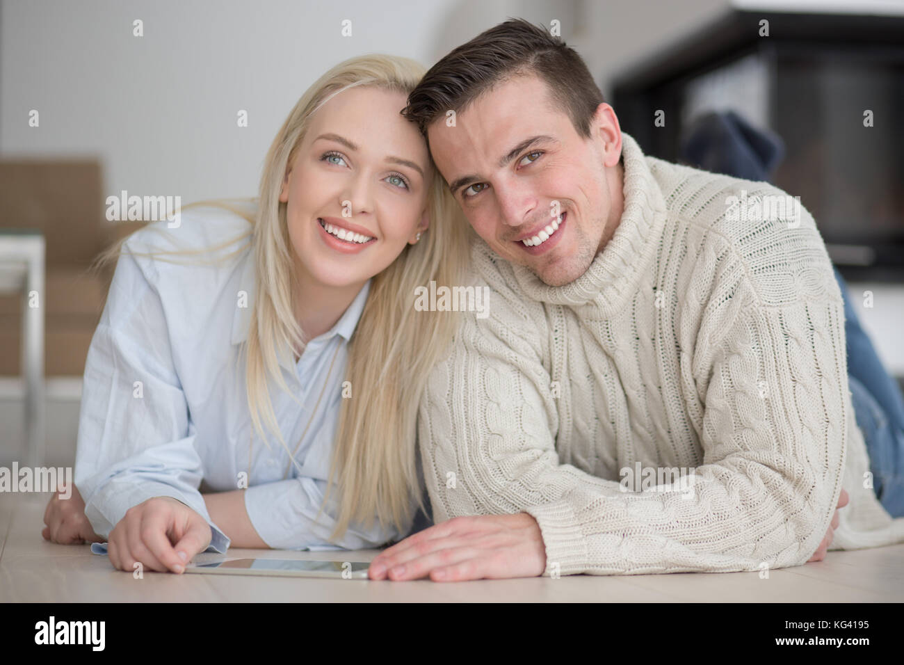 Jeune couple sur le sol en face de cheminée internet surf using digital tablet on froide journée d'hiver Banque D'Images