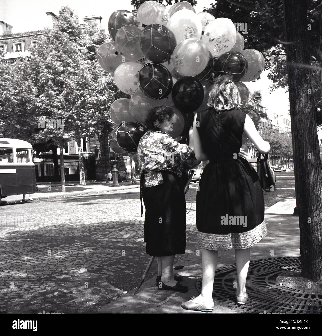 Années 1950, historiques, une dame l'achat de ballons une vieille femme vendeur de rue à Paris, France. Banque D'Images