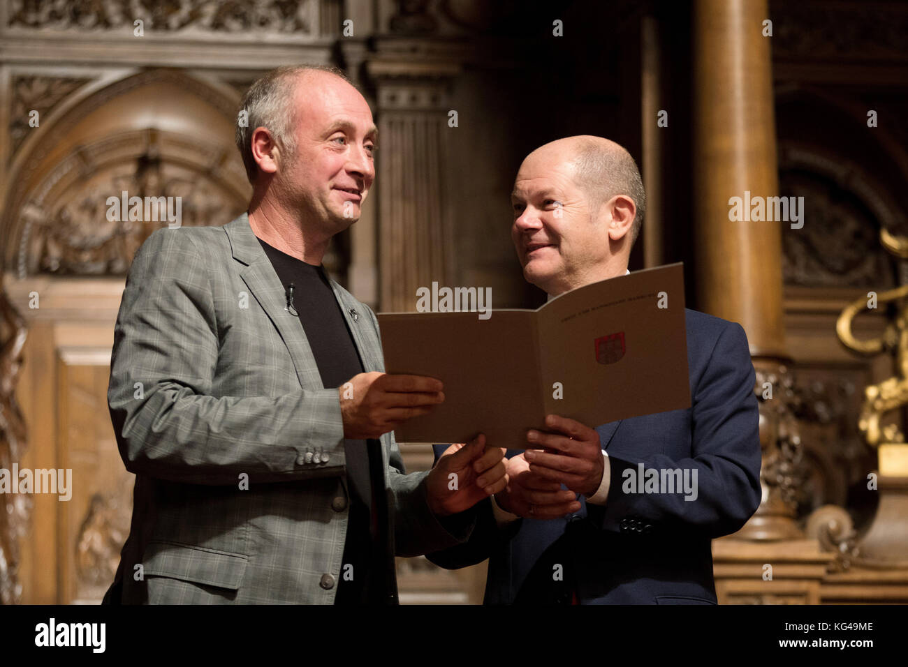 L'artiste de cabaret, Emmanuel peterfalvi (l), présente une bouteille de vin rouge pour le premier maire de Hambourg d'Olaf Scholz le parti social-démocrate d'Allemagne (SPD) après la 42e cérémonie de naturalisation dans le grand hall de l'hôtel de ville de Hambourg le 03 novembre 2017. Le comédien de paris connu sous le nom de alfons a obtenu la citoyenneté allemande vendredi. plus de 100 autochtones de Hambourg ont célébré leur naturalisation à l'hôtel de ville cérémonie. photo : christian charisius/dpa Banque D'Images