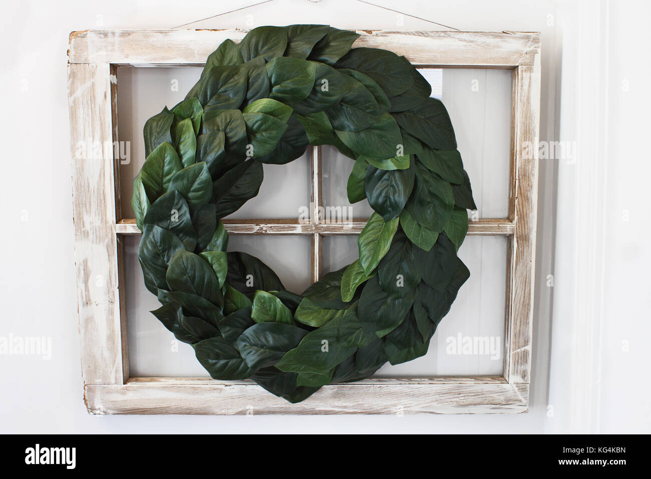 Fenêtre ancienne ferme décorée avec une couronne de feuilles de magnolia maison accrochées sur un mur intérieur. Banque D'Images