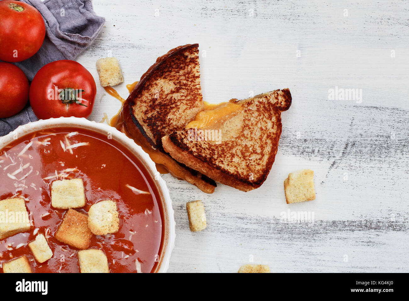 Soupe de tomate chaud avec du parmesan et croûtons servis avec un sandwich au fromage. image en plongée des mises à plat dans le style. Banque D'Images