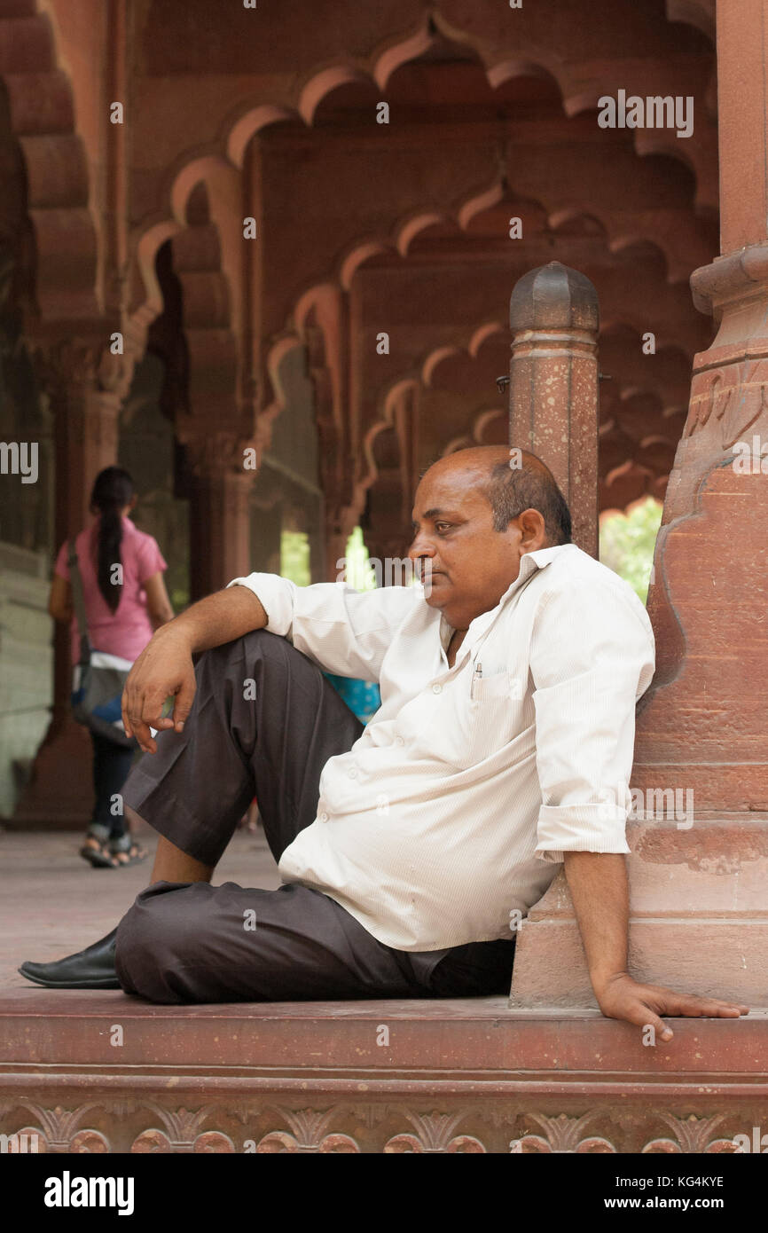 Homme assis appuyé sur la colonne en face de la colonnade voûtée, Inde Banque D'Images