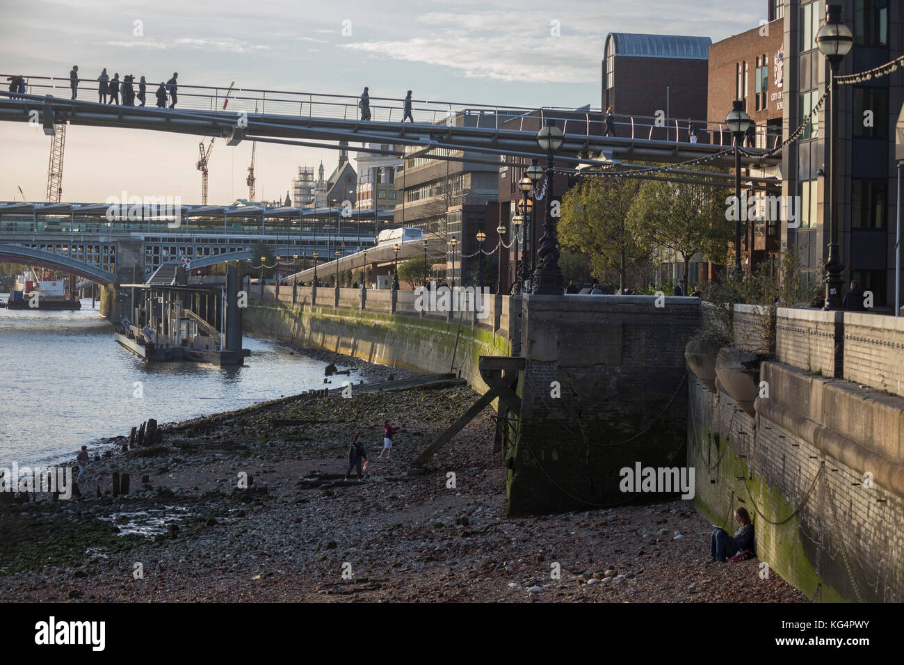 Un artiste est assis contre le mur de la rivière et d'autres jouent sur la boue à marée basse à des piétons sur le pont du millénaire à pied les frais généraux, le 30 octobre 2017, dans la ville de Londres, en Angleterre. Banque D'Images