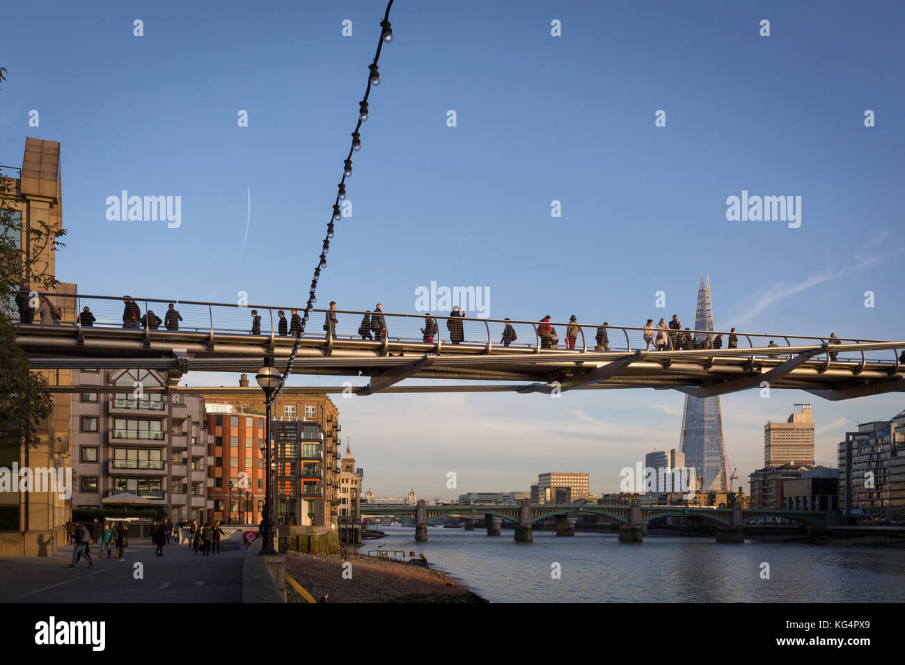 En fin d'après-midi et soleil d'automne avec la grande punto de la gratte-ciel d'échardes dans la distance, les piétons marcher sur le Millennium Bridge sur la Tamise, le 30 octobre 2017, dans la ville de Londres, en Angleterre. Banque D'Images