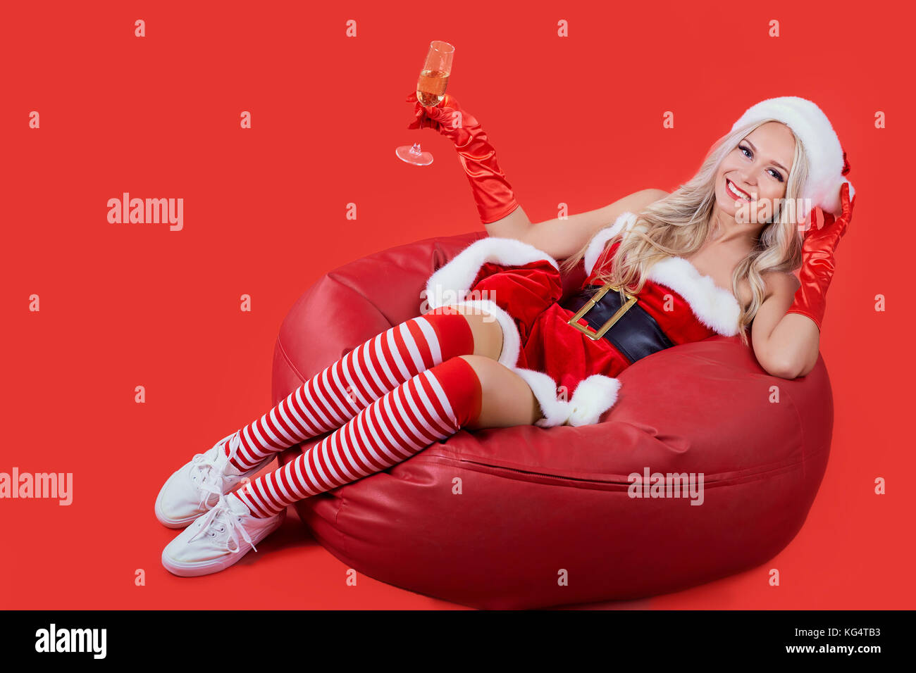 Une petite fille en costume père noël assis sur un fond de noël. Banque D'Images