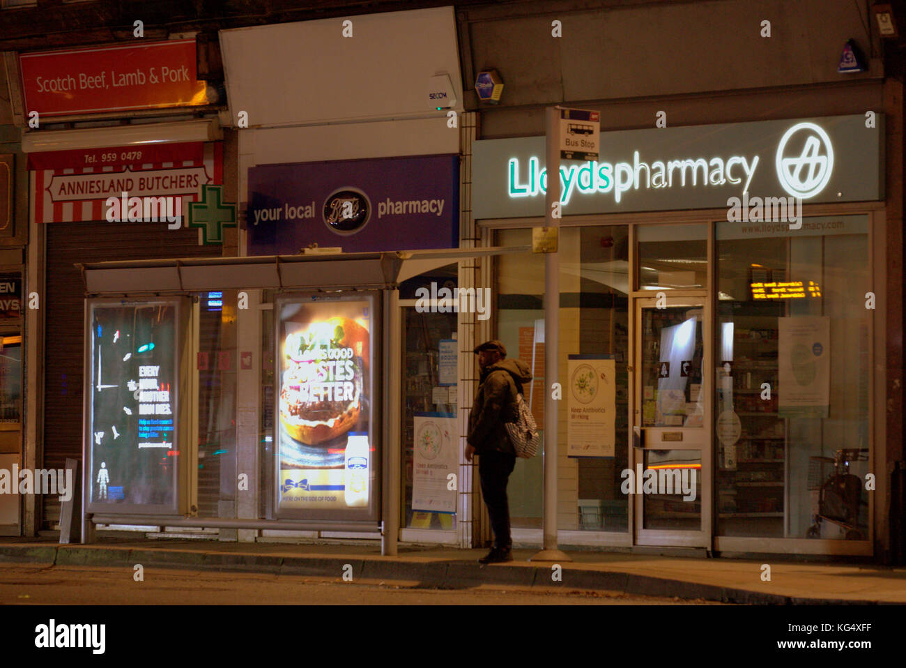 L'homme en attente à l'arrêt de bus sur la rue pour la fin de l'autobus de nuit anniesland cross Glasgow Banque D'Images
