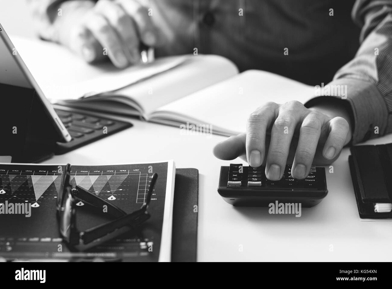 Businessman hand travaillant avec des finances à propos des coûts et calculatrice et latop avec téléphone mobile sur withe bureau bureau moderne en noir et blanc, Banque D'Images