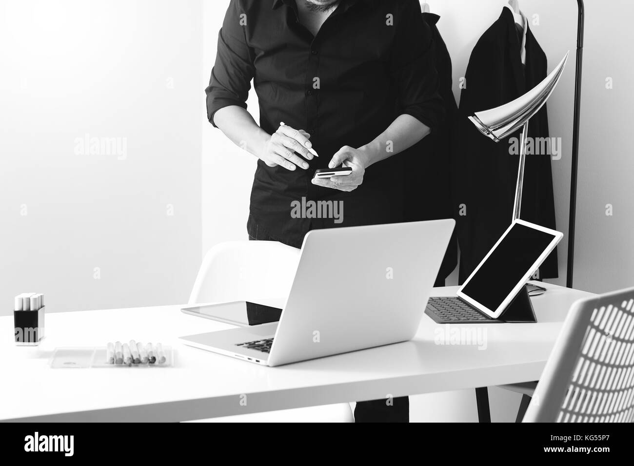 Créateur de mode de travail avec téléphone mobile et ordinateur portable avec l'aide de l'ordinateur tablette numérique en studio moderne noir et blanc, Banque D'Images