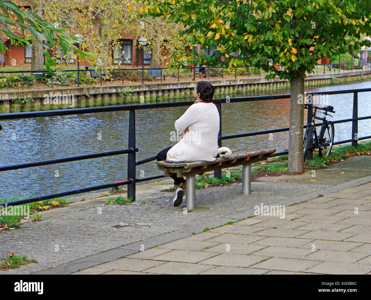 Une femme d'âge moyen assis sur un siège et regardant à travers une rivière. Banque D'Images