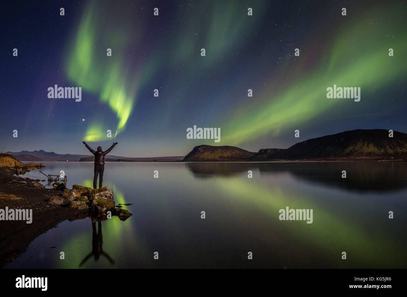 Femme profiter de la vue de la northern lights, au lac, l'islande thingvellir. Le parc national de thingvellir est un unesco world heritage site. Banque D'Images