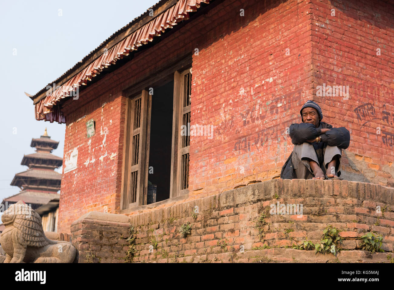 Bhaktapur, Katmandou, Népal, zone bagmati homme assis sur le mur de Bhaktapur place avec le temple derrière lui Banque D'Images