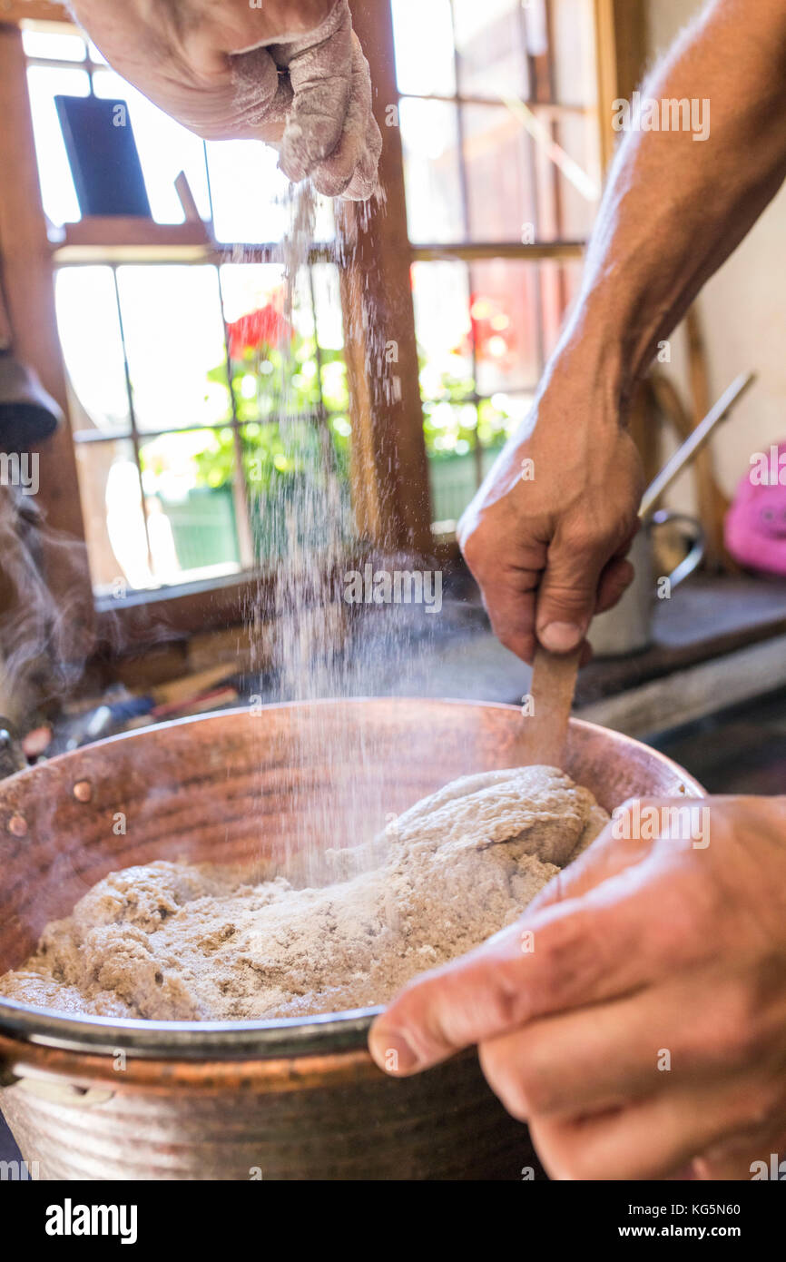 Cuisinier, mélanger les ingrédients de la polenta typique, San Romerio Alp, Grisons, Canton des Grisons, vallée de Poschiavo, Suisse Banque D'Images