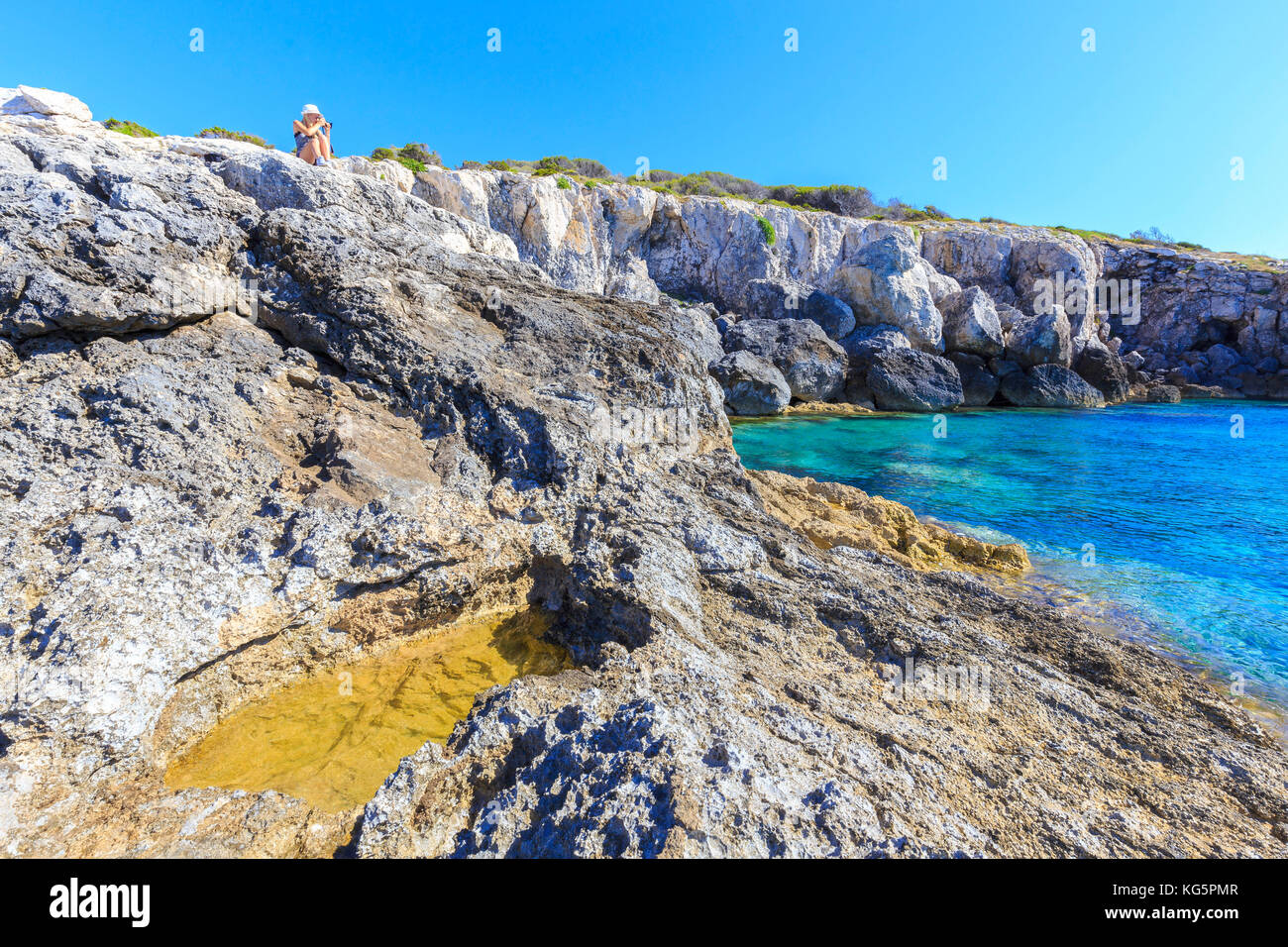 Photographe en action sur les rochers de Cala dei benedettini, îles Tremiti, Foggia, Pouilles, Italie. Banque D'Images