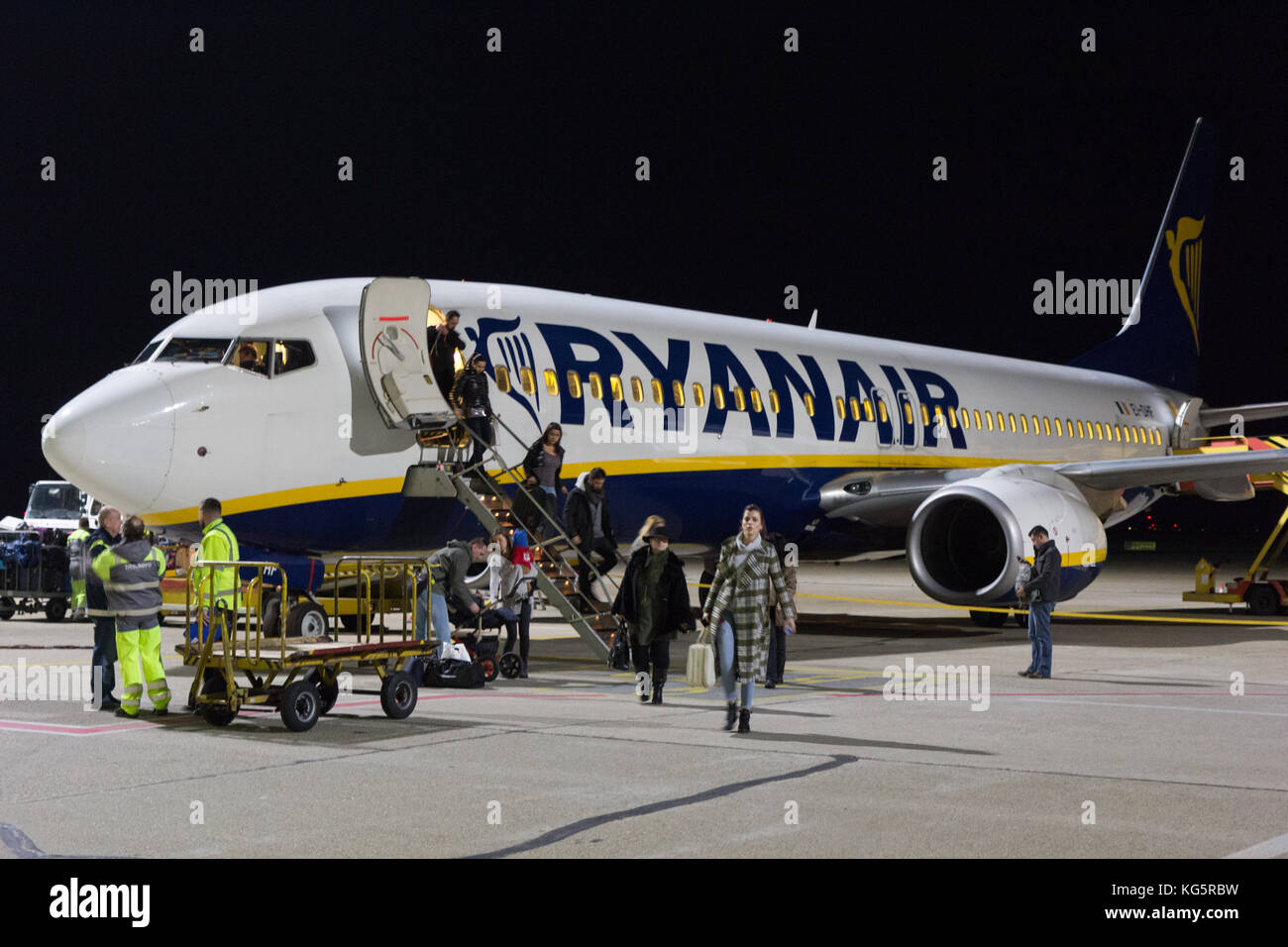 Un Boeing 737-800 de Ryanair stationné à l'aéroport de Bratislava la piste de nuit. Les gens sortent de l'avion. Banque D'Images