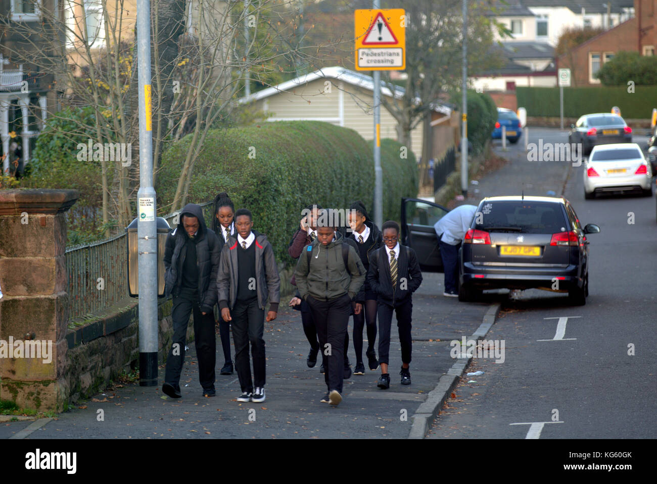 Grand groupe d'écoliers noirs à l'arrêt de bus demande de signal pour monter à bord de la rue Jordanhill image de nouvelles Banque D'Images