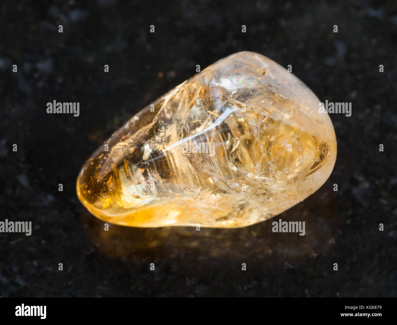La prise de vue macro des eaux minérales naturelles rock specimen - tumbled citrine gemstone sur fond de granit sombre Banque D'Images