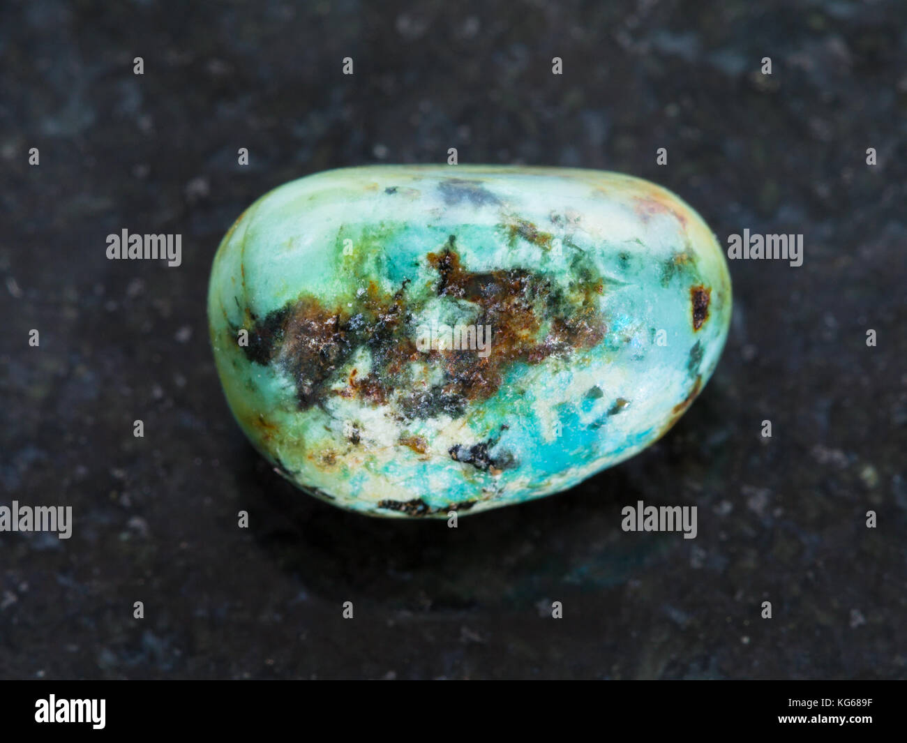La prise de vue macro des eaux minérales naturelles rock specimen - tumbled gemstone turquoise sur fond de granit sombre Banque D'Images