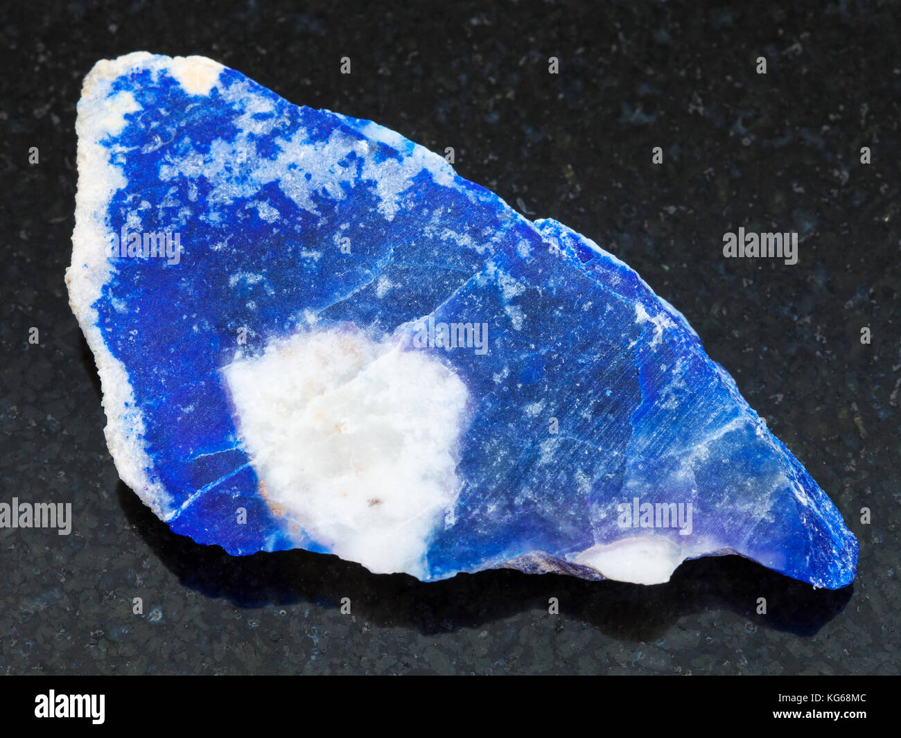 La prise de vue macro des eaux minérales naturelles rock specimen - rough lazurite (lapis-lazuli) sur la pierre de granit sombre contexte Banque D'Images