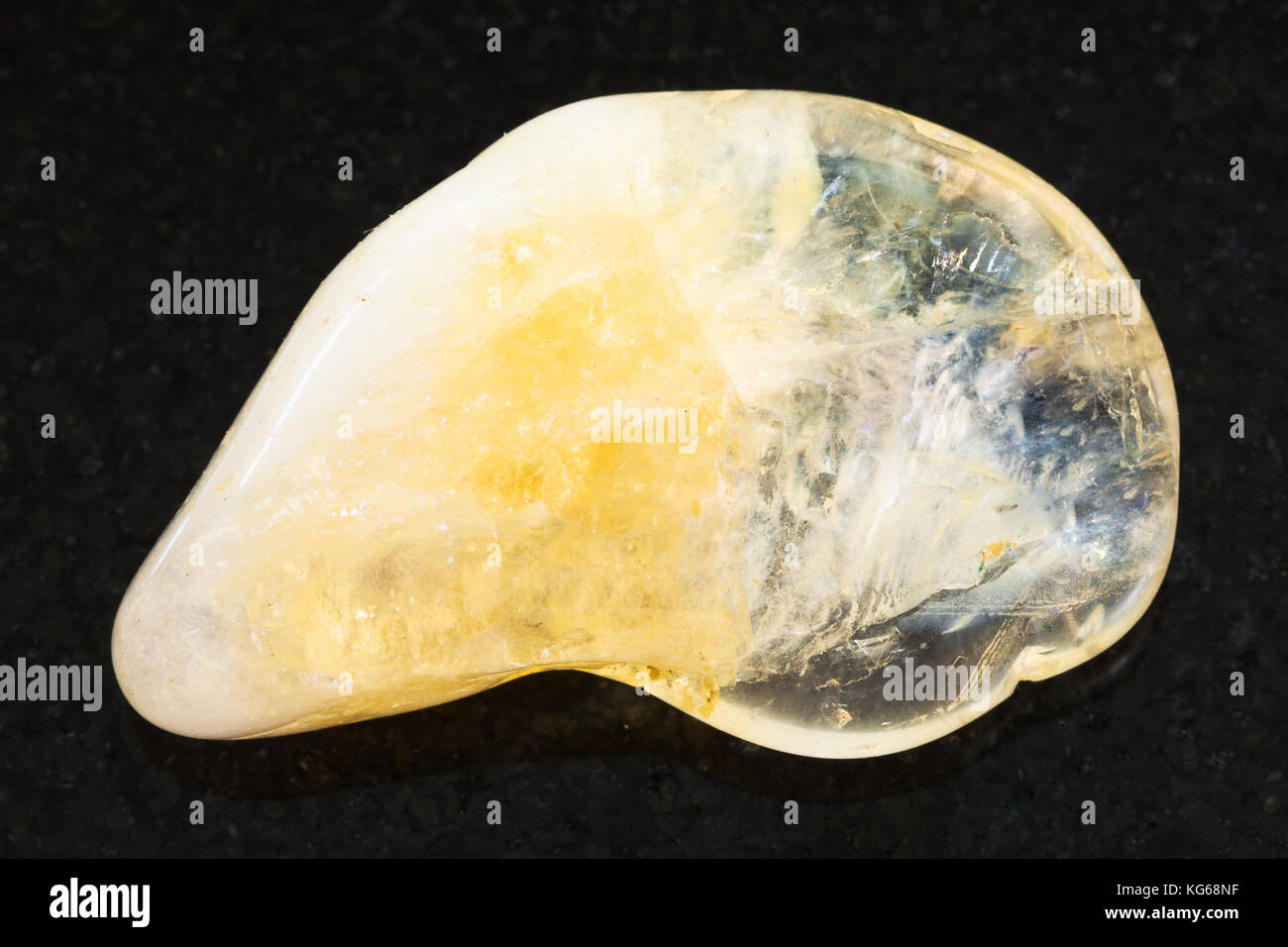 La prise de vue macro des eaux minérales naturelles rock specimen - citrine jaune poli sur fond de granit noir de pierre gemme Banque D'Images
