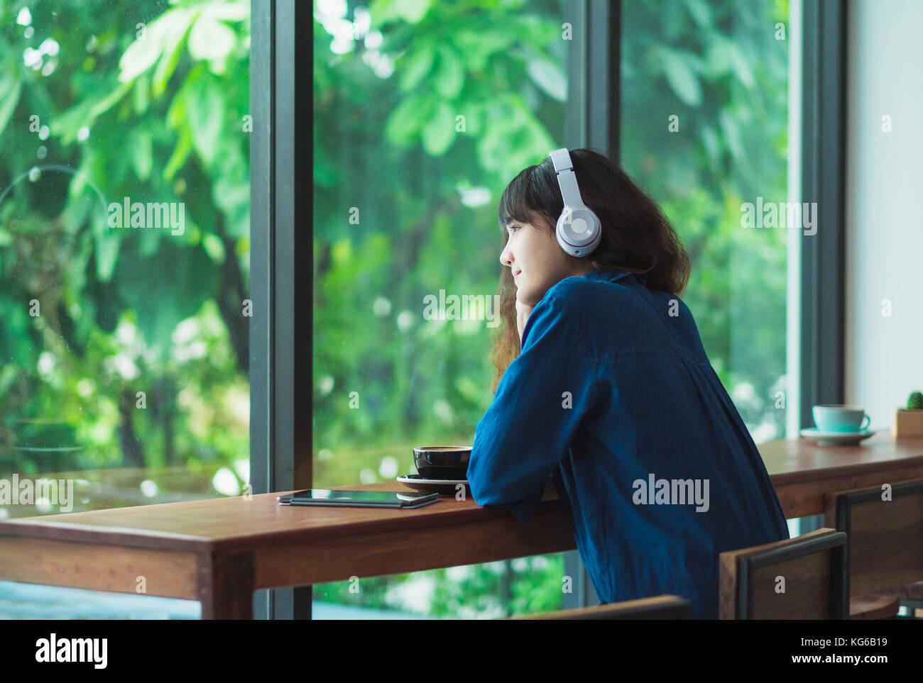 Happy asian casual woman listening music with headphones près de fenêtre à cafe restaurant,l'âge numérique,style de vie chill out. Banque D'Images