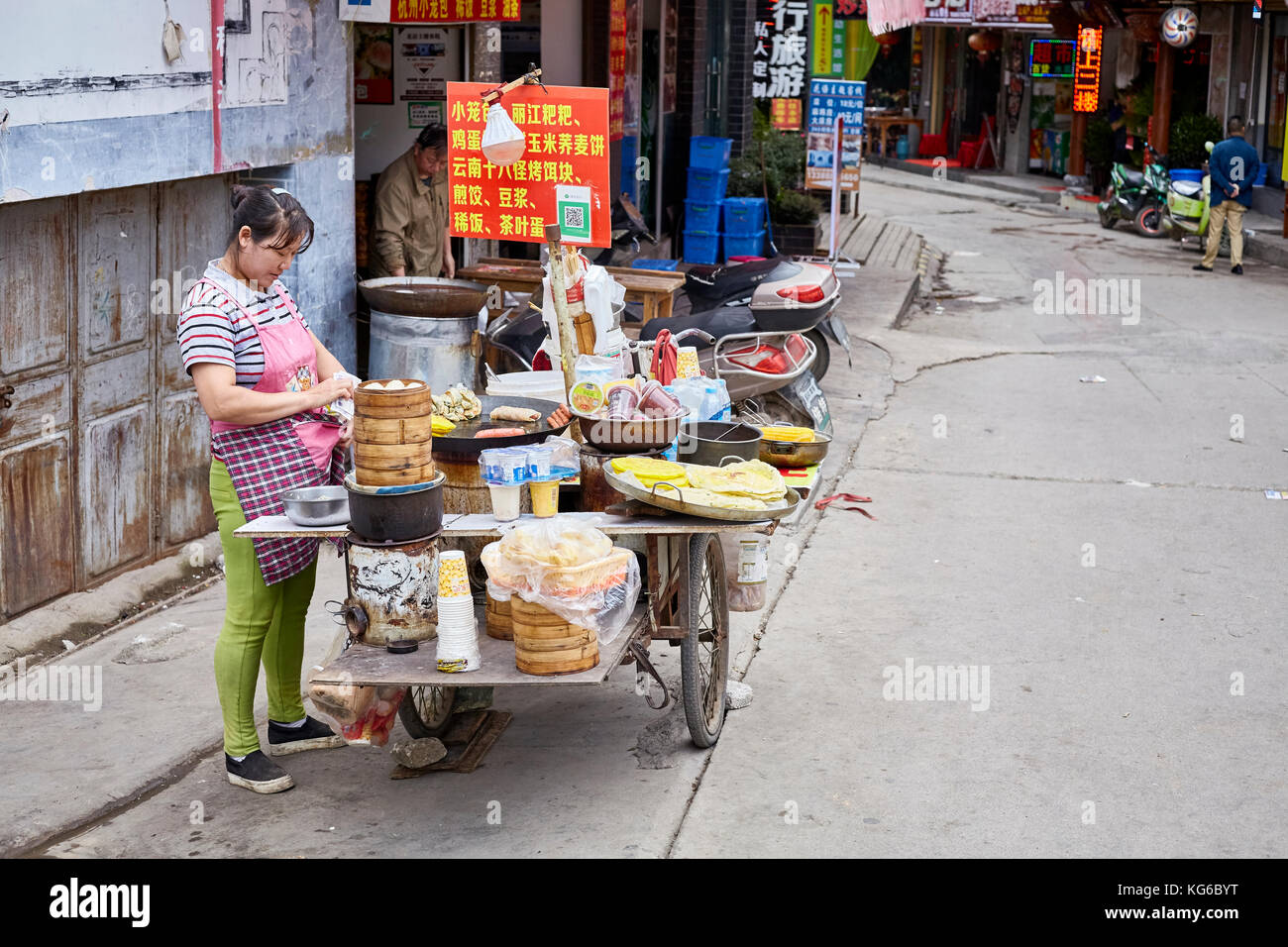 Lijiang, Yunnan, Chine - le 27 septembre 2017 : femme prépare et vend des hôtes des aliments à des wc séparés. Le paiement via QR code devient très commun en Chi Banque D'Images