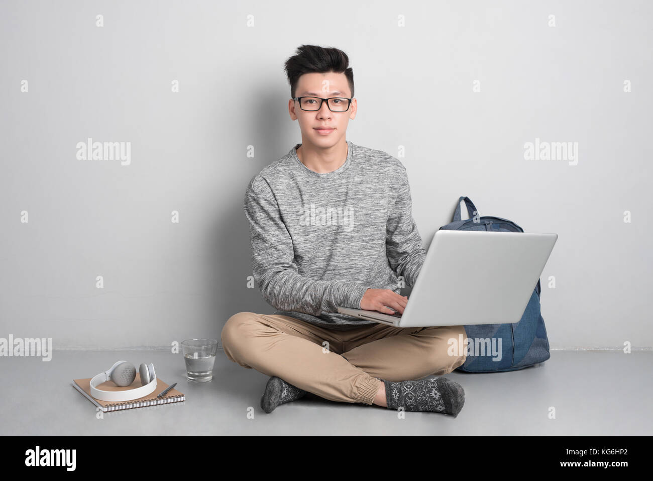 Jeune homme assis sur le plancher et à l'aide d'ordinateur portable. Banque D'Images