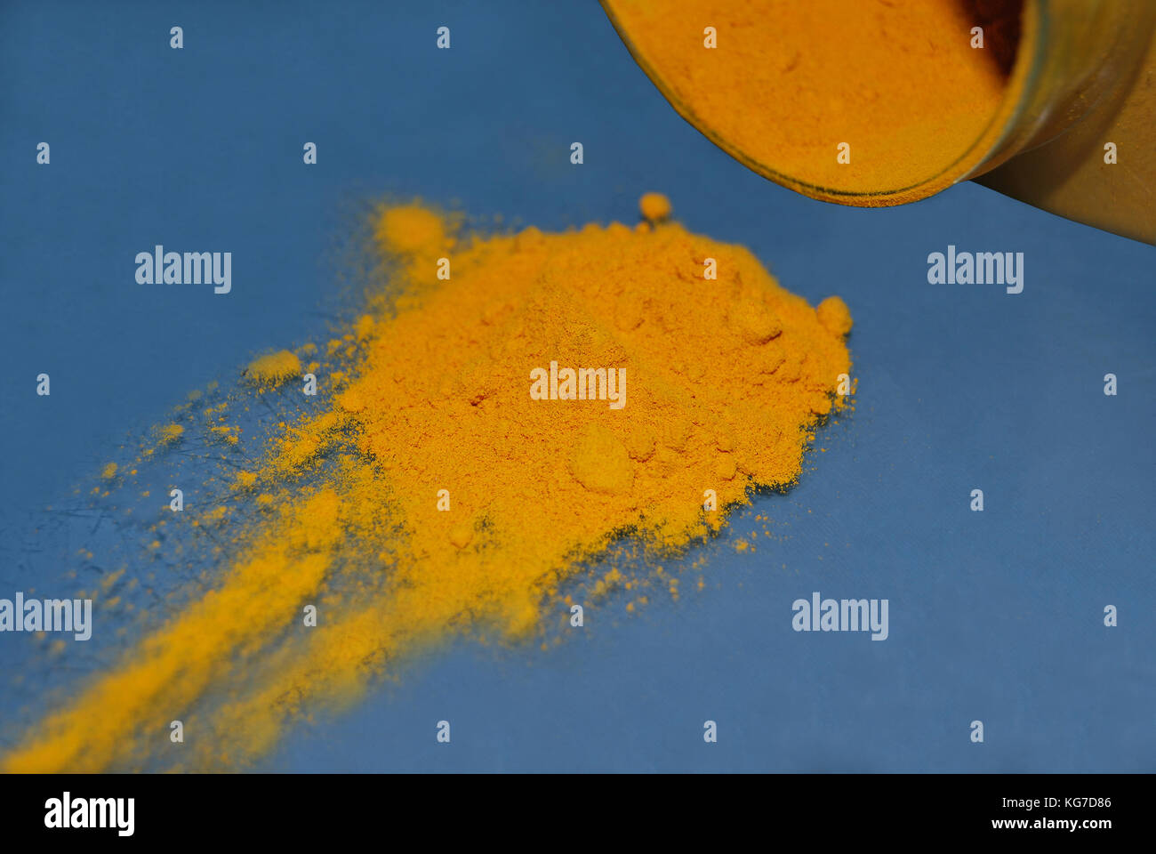Le curcuma jaune dispersés d'un pot d'assaisonnement sur un tableau bleu Banque D'Images