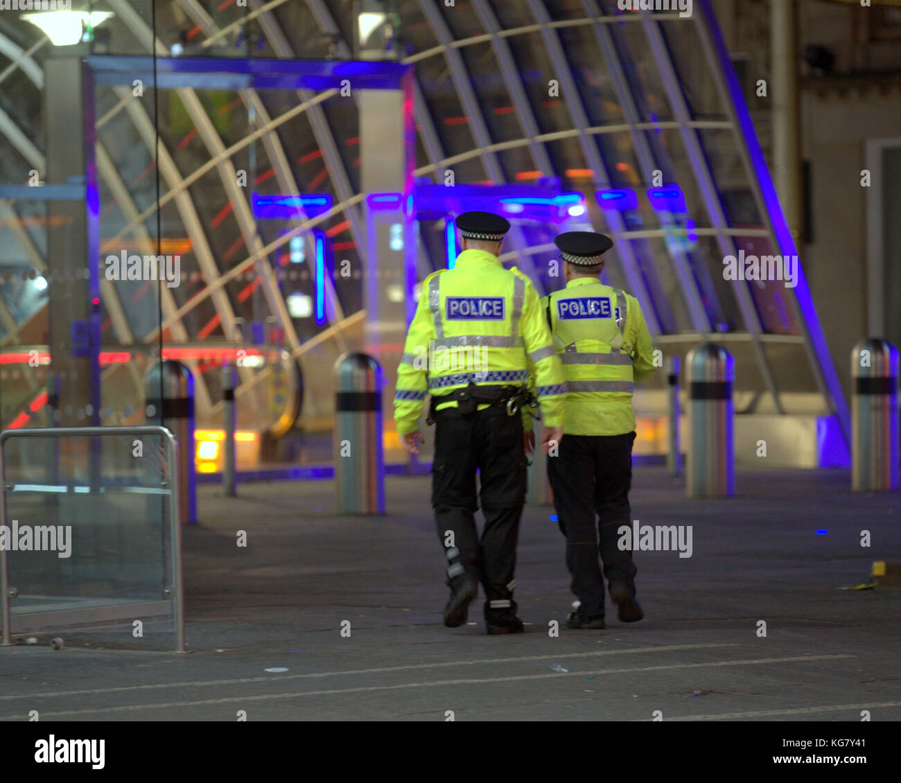 Deux policiers de la police l'Ecosse vu de derrière d'entrer à l'entrée du métro au néon nuit Glasgow city, united kingdom Banque D'Images