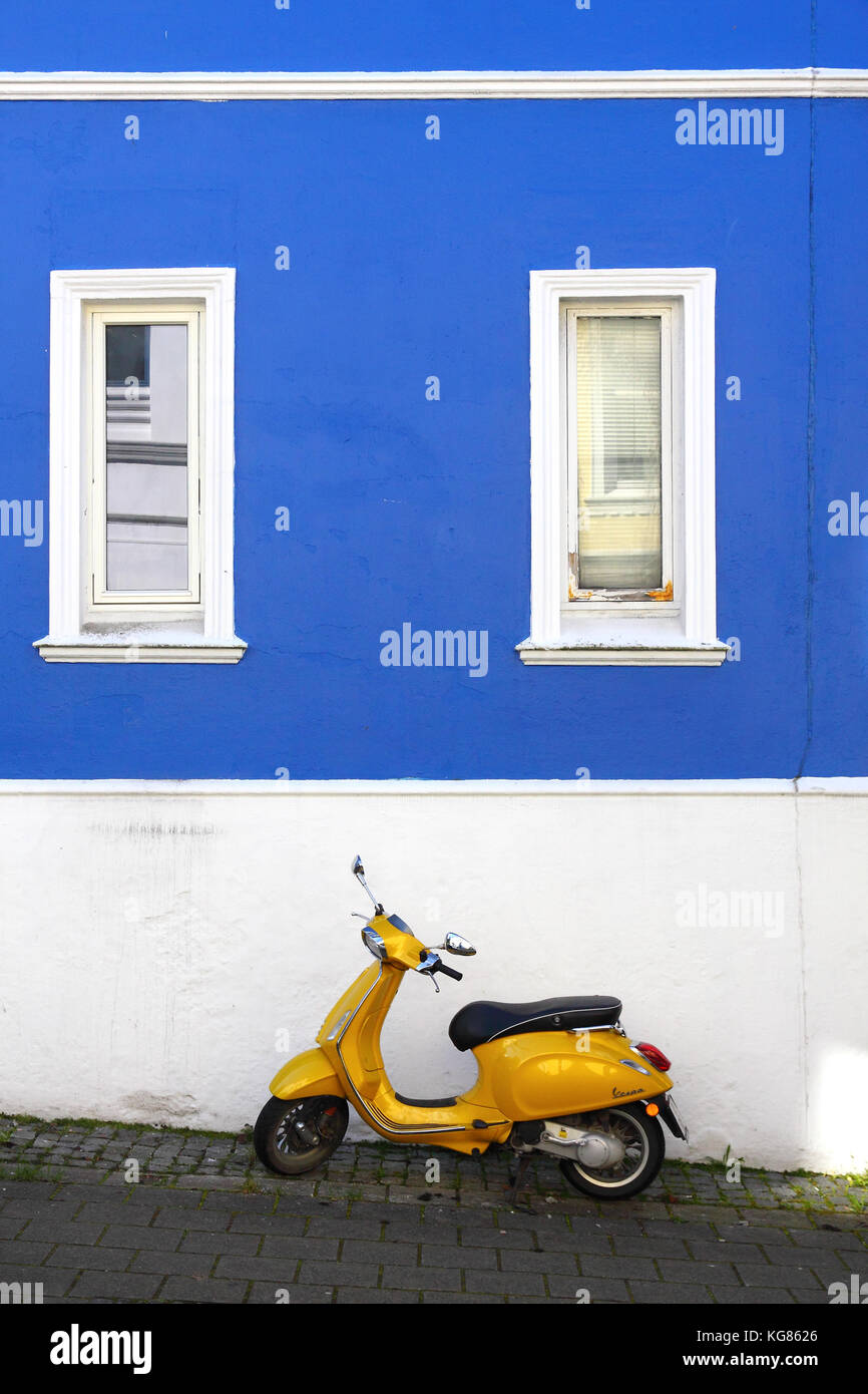 Scooter jaune sur bleu et blanc mur dans la zone résidentielle Skuteviken de Bergen, Norvège Banque D'Images