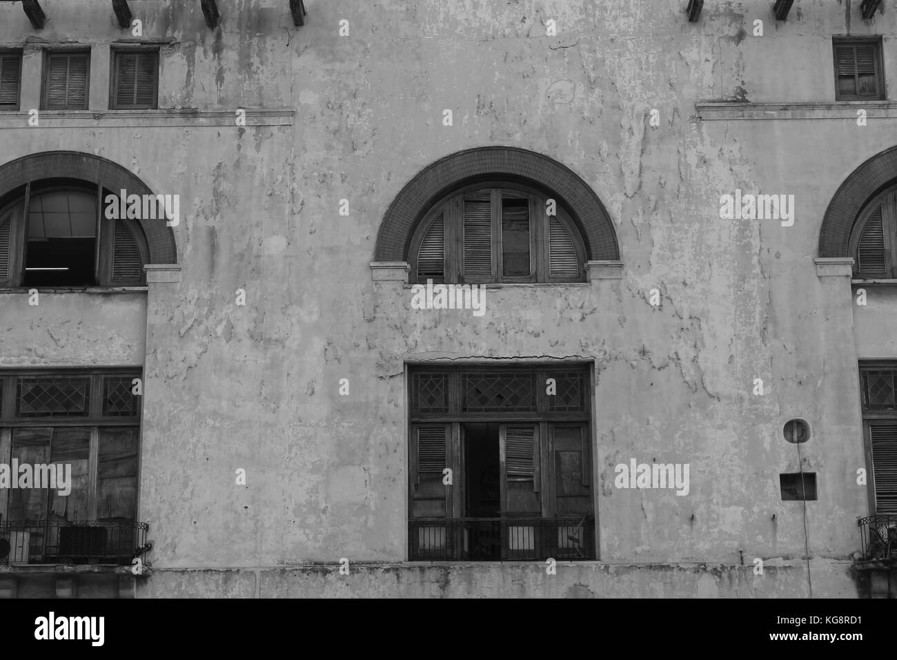Vieux bâtiment de style espagnol, le ciment, La Havane, Cuba. Les cadres de fenêtres cintrées, volets et portes cassées, ébréchées et peler la peinture. Le noir et blanc Banque D'Images