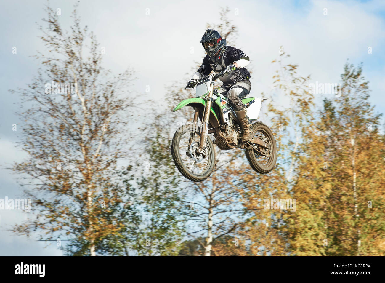 Pilote moto voler sur la piste au motocross, les arbres d'automne sur l'arrière-plan Banque D'Images