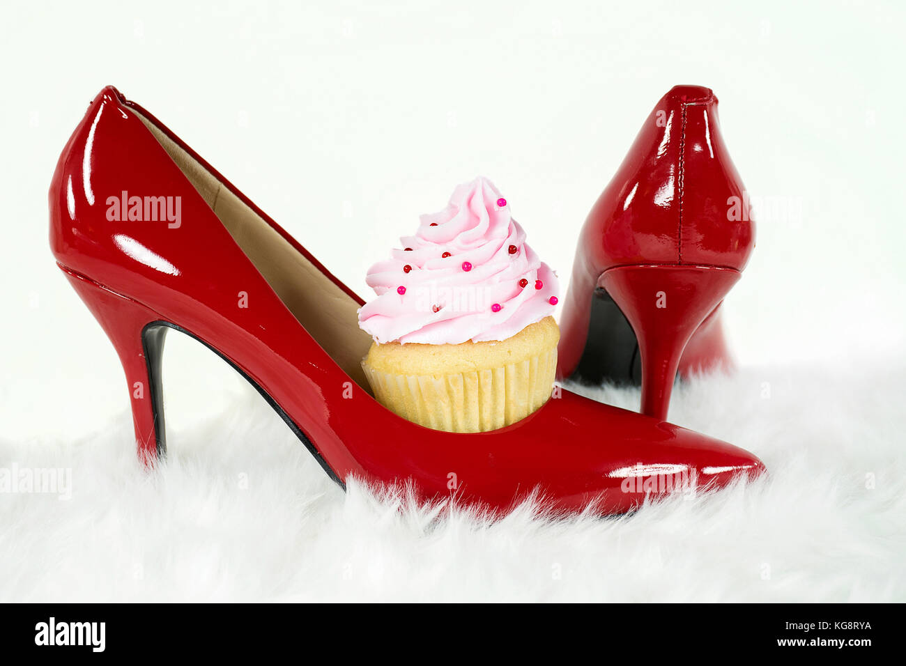 Avec cupcake cerise rose en rouge chaussure haut talon sur la fourrure blanche Banque D'Images
