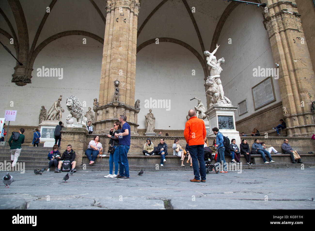 Scène de rue à la Medici piazza montrant les touristes le repos, l'pidgeons, et des sculptures avec des piliers Banque D'Images