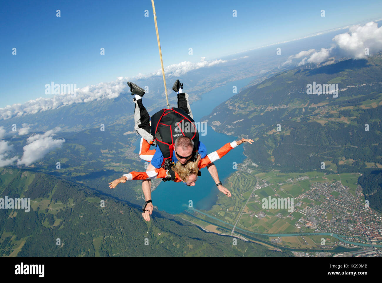 Cette skydiving tandem couple est tomber gratuitement plus d'une vue magnifique sur la montagne et la superficie du lac. Le bonheur est à voir sur leurs visages smiley. Banque D'Images