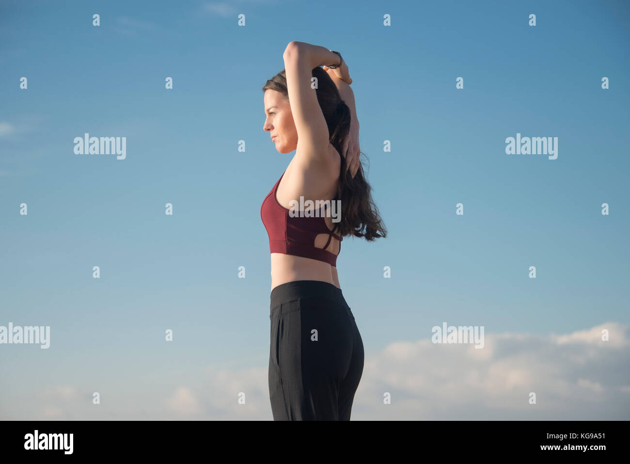 Femme sportive portant un soutien-gorge de sport faisant un bras s'étendent en dehors de garder l'ajustement. Banque D'Images