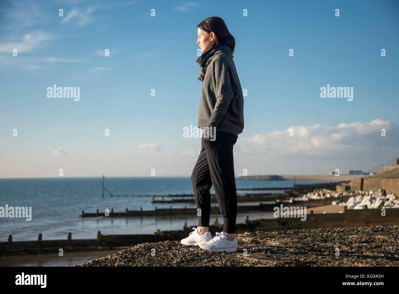 Femme debout avec les mains dans les poches regardant la mer Banque D'Images Femme debout avec les mains dans les poches regardant la mer Banque D'Images