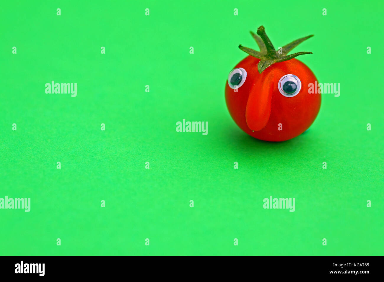 Tomate cerise mûre fraîche avec un visage sur un fond uni avec copie espace Banque D'Images