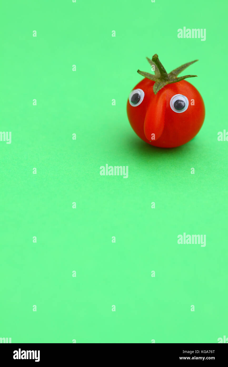 Tomate cerise mûre fraîche avec un visage sur un fond uni avec copie espace Banque D'Images