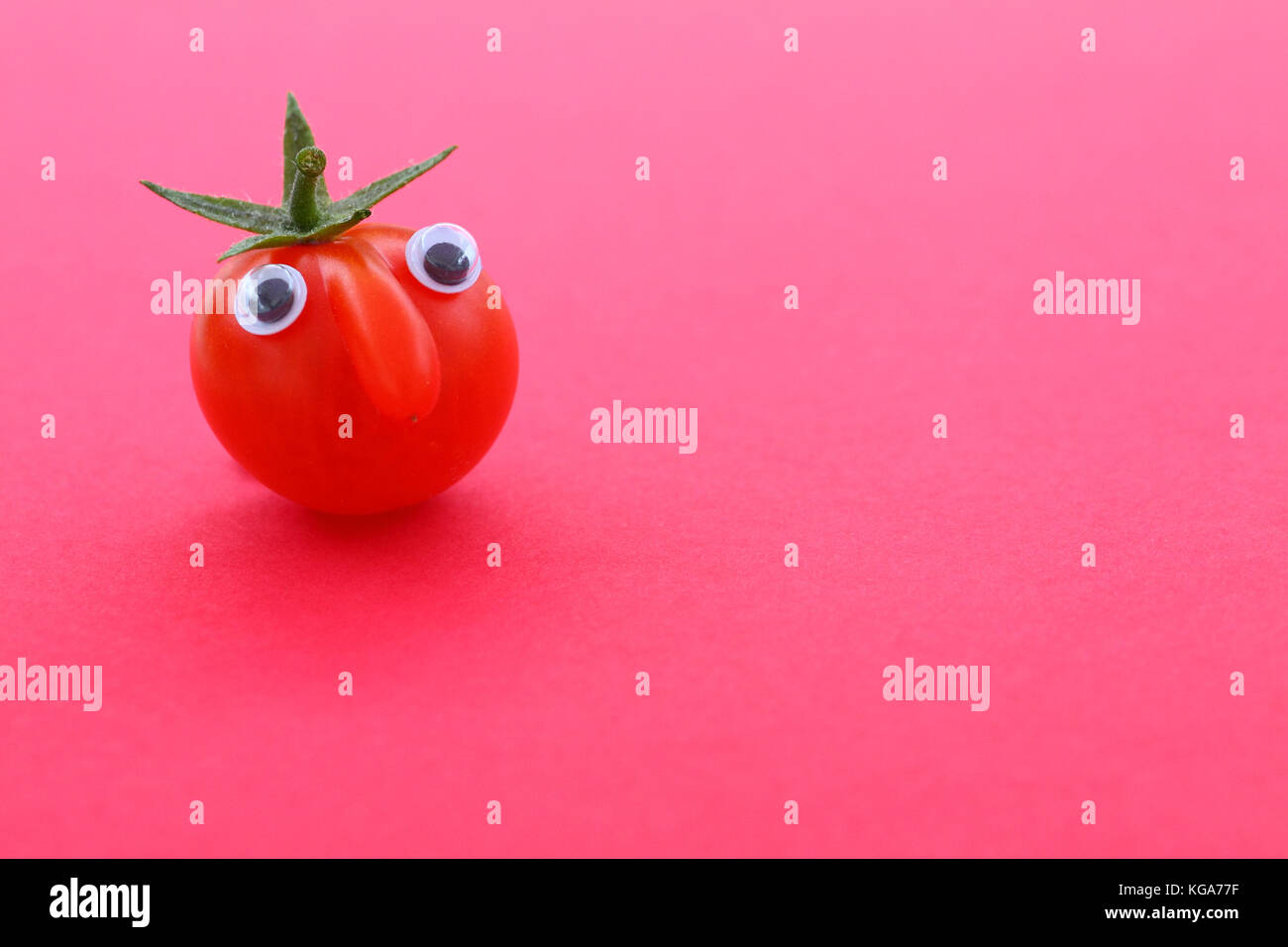 Tomate cerise mûre fraîche avec un visage sur un fond uni avec copie espace Banque D'Images