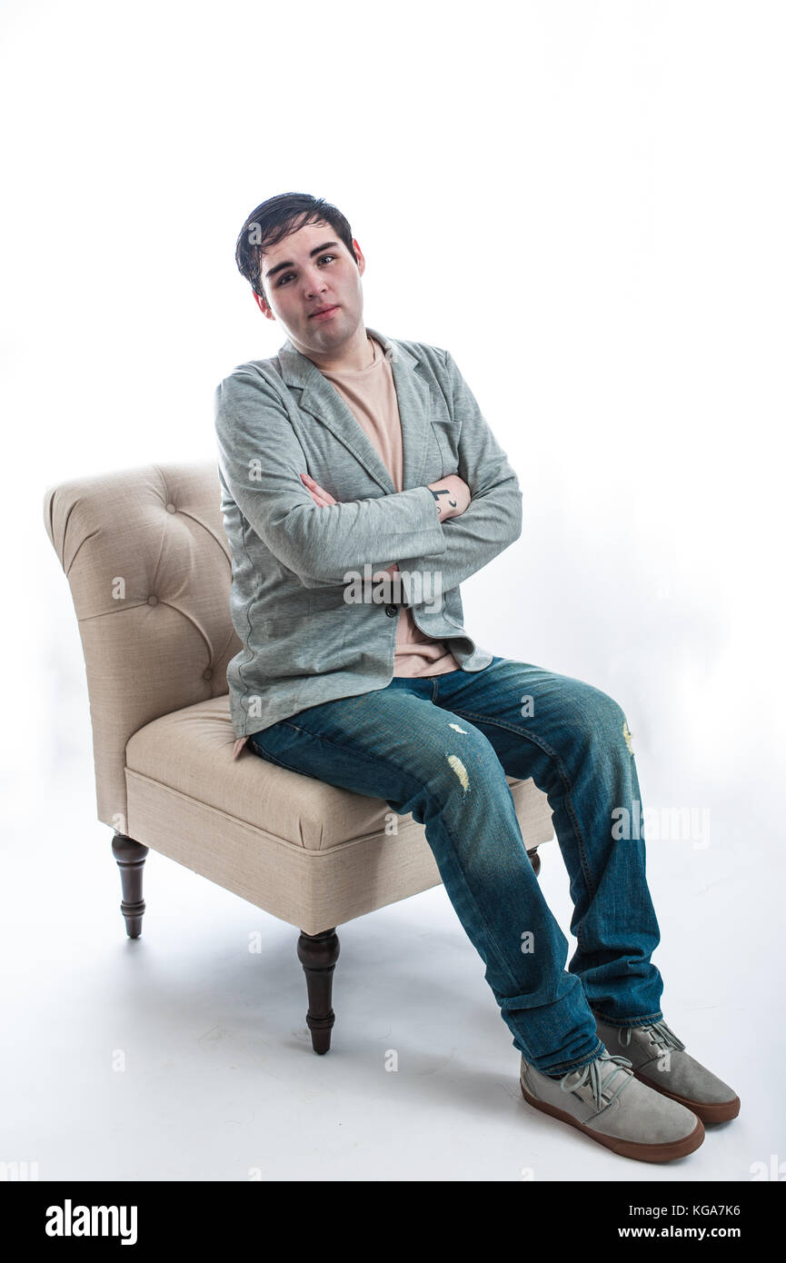 Jeune homme à peau claire assis sur une chaise à la hâte avec les bras croisés. Banque D'Images