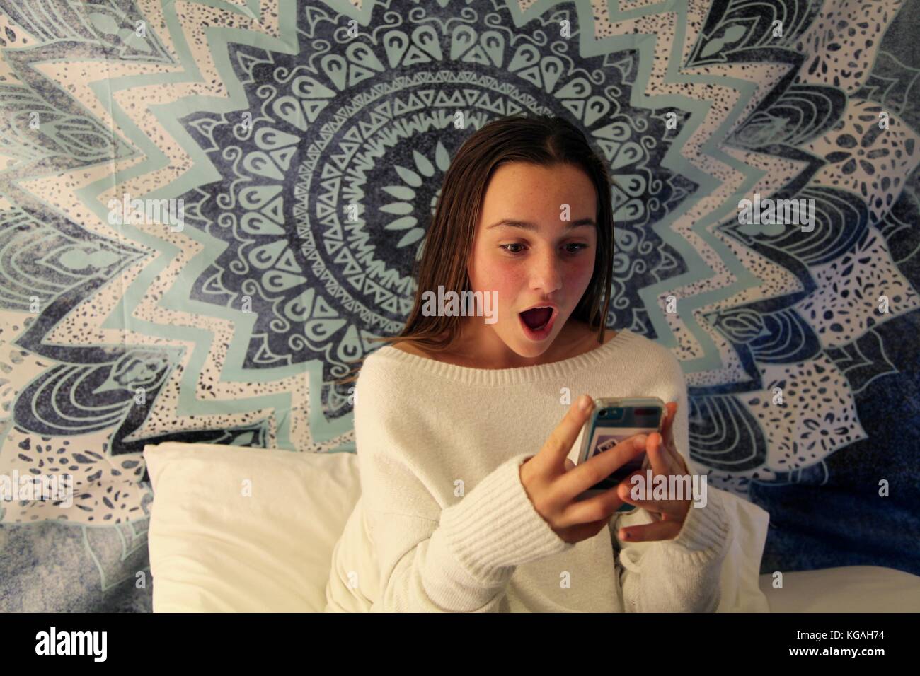 Jeune adolescente des sms sur un téléphone mobile, l'air choqué de l'écran Banque D'Images