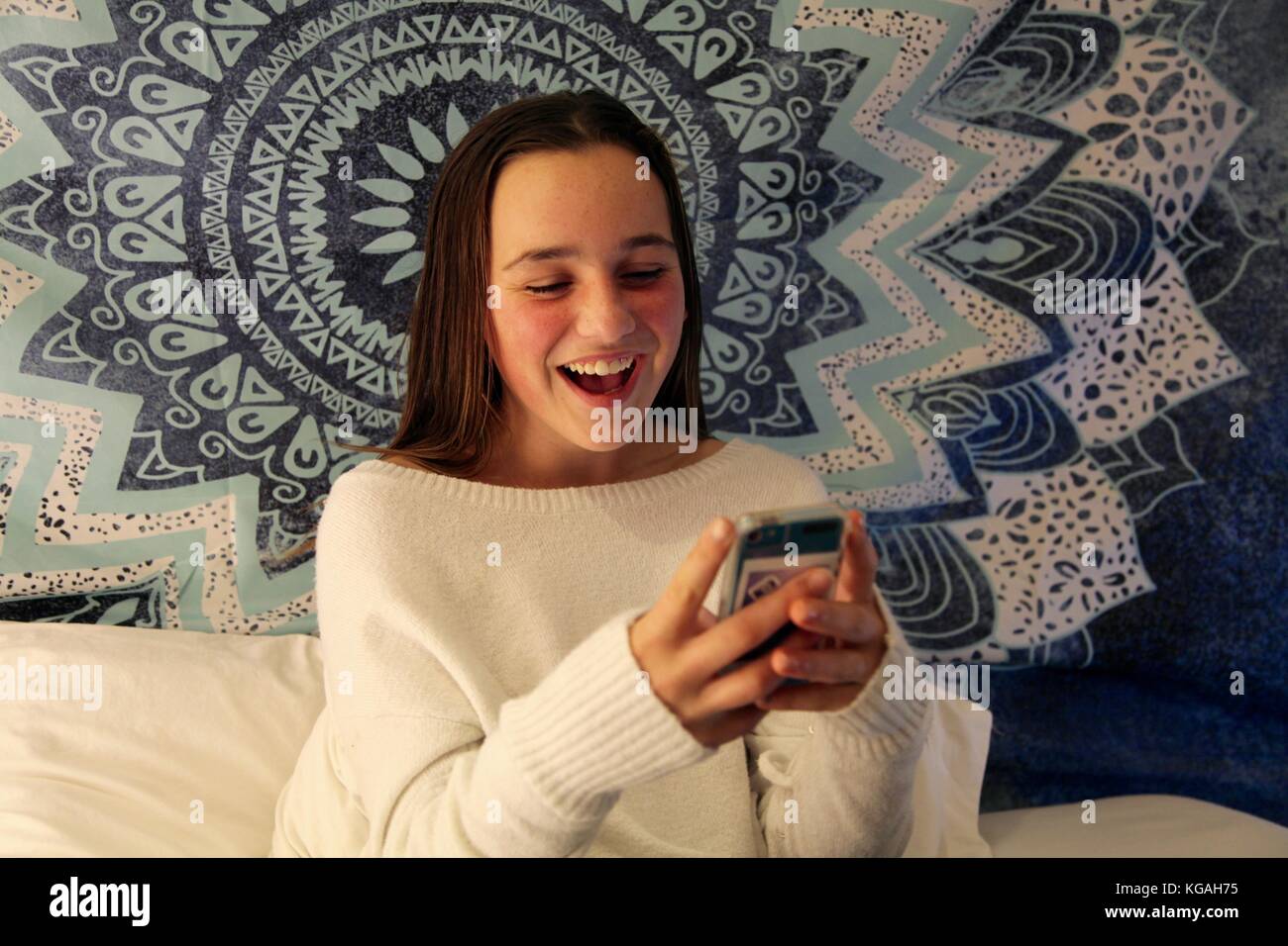 Woman texting on her smart phone dans sa chambre à coucher Banque D'Images