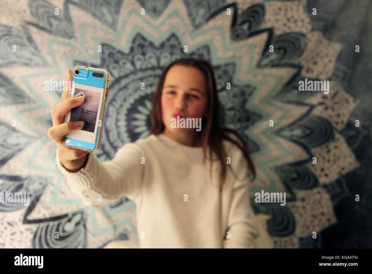 Jeune adolescente prenant un sur son téléphone portable selfies devant un arrière-plan à la mode Banque D'Images