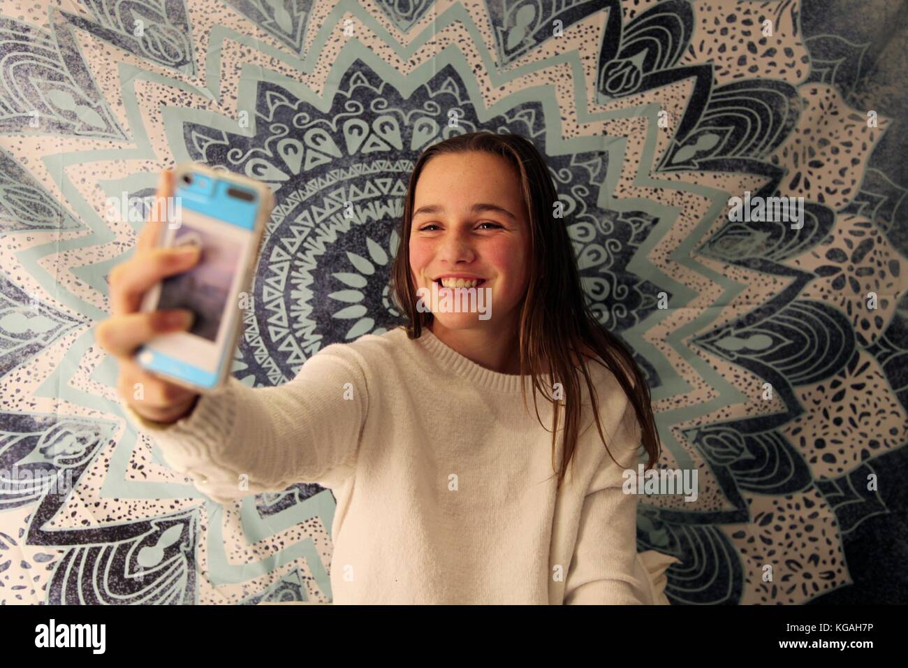 Jeune adolescente prenant un sur son téléphone portable selfies devant un arrière-plan à la mode Banque D'Images