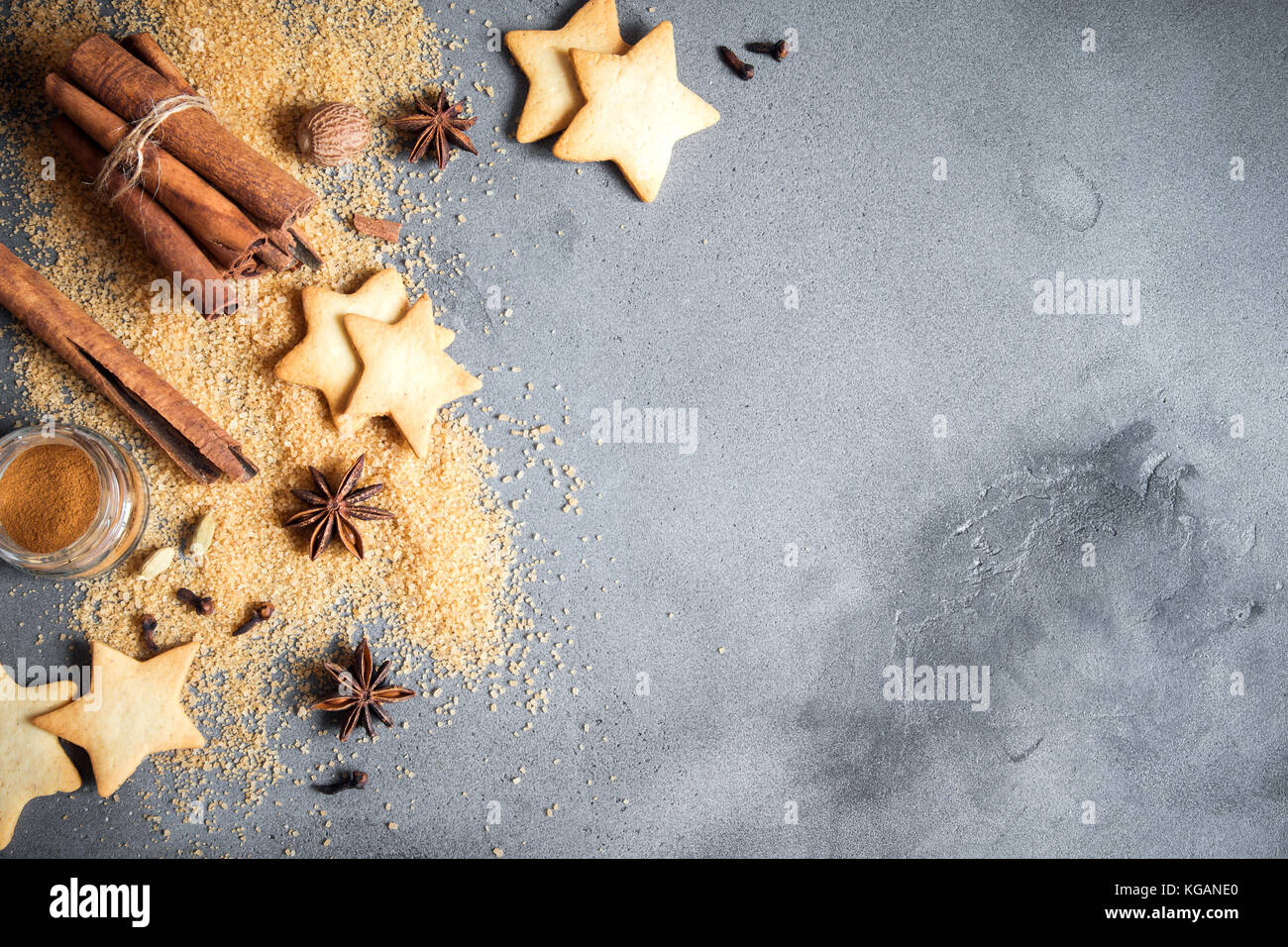 Épices de Noël, Christmas et ingrédients sur fond de béton gris. cannelle, anis étoile, muscade, cardamome, clou de girofle, le sucre brun Banque D'Images