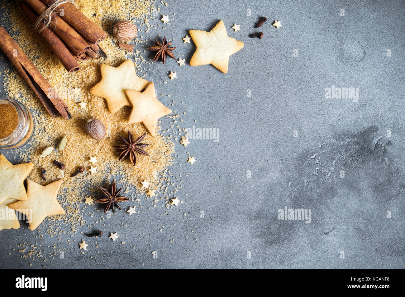 Épices de Noël, Christmas et ingrédients sur fond de béton gris. cannelle, anis étoile, muscade, cardamome, clou de girofle, le sucre brun Banque D'Images