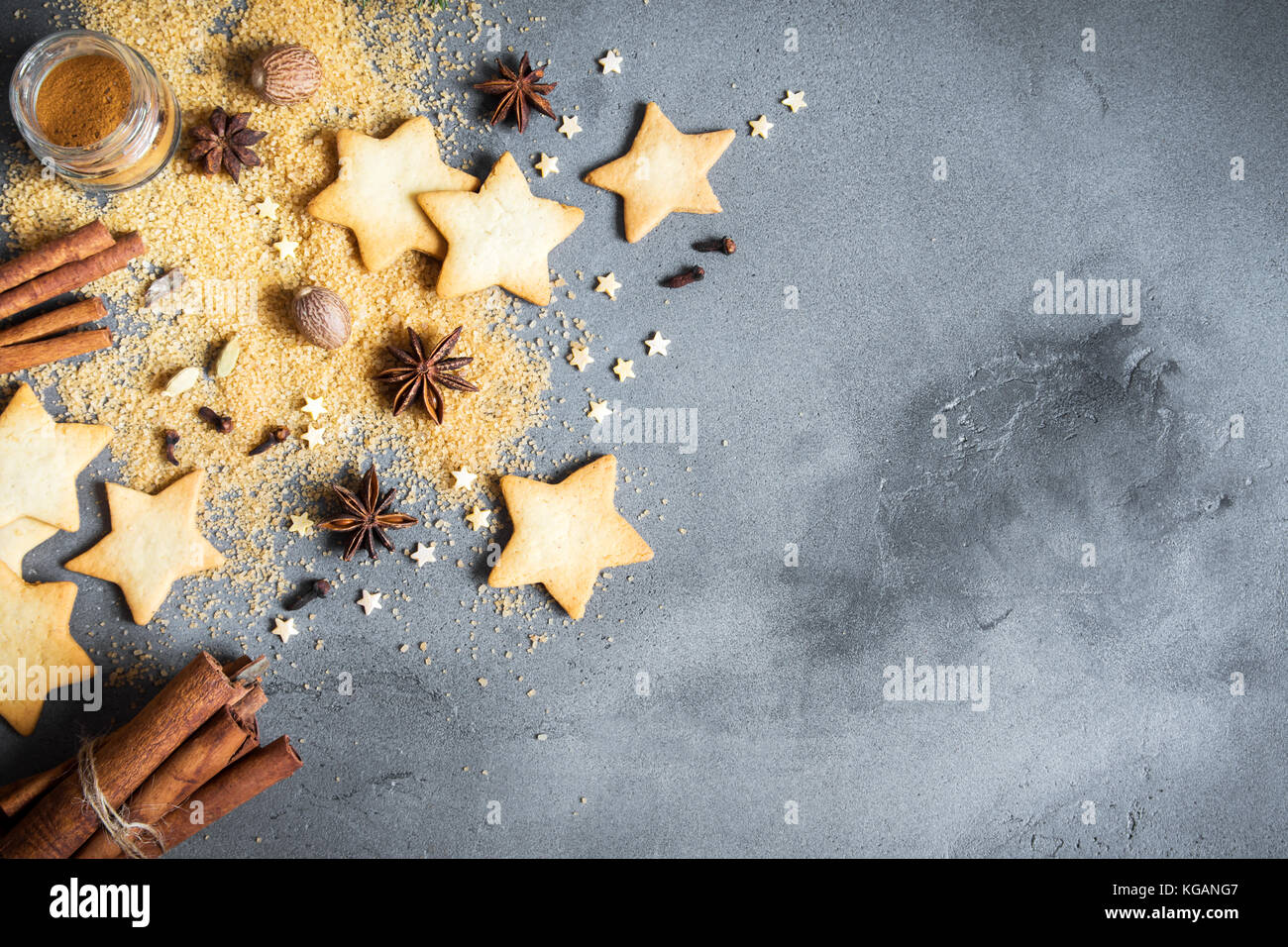 Épices de Noël, Christmas et ingrédients sur fond de béton gris. cannelle, anis étoile, muscade, cardamome, clou de girofle, le sucre brun Banque D'Images