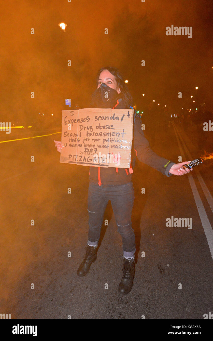 Femelle avec flare et message. Masque de millions pour les sans-voix anonyme Mars manifestation de protestation à travers Londres sur la nuit de Guy Fawkes, le 5 novembre Banque D'Images